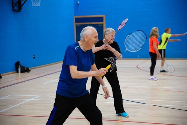 Personas mayores jugando al bádminton en un pabellón