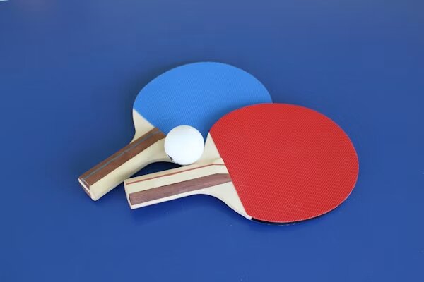 Dos palas y pelota sobre mesa azul
